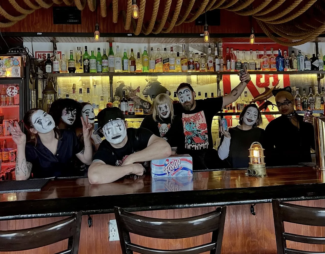The NSYC crew in juggalo face paint behind the bar with a case of Faygo